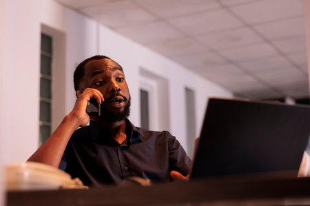 Financial analyst discussing company report with colleague on smartphone, african american man...