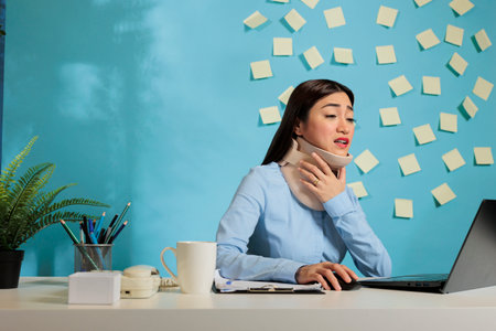 Asian woman wearing cervical collar to recover from injury. Office employee with fractured vertebrae...