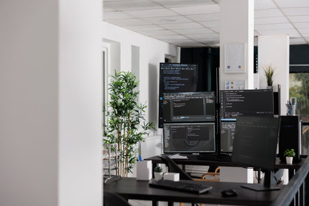 Empty programming office with computer monitors on desk, computers in background running html code...