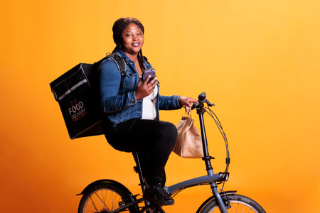 African american restaurant courier looking at client adreess on smartphone before start delivering...