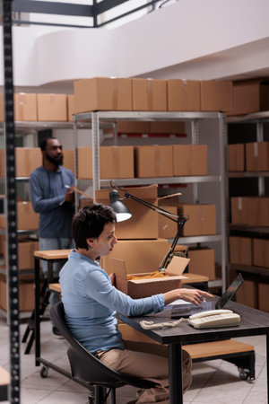 Woman supervisor looking at cargo stock on laptop computer while checking fashion blouse status...