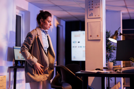 Overworked entrepreneur preparing to leave corporate job late at night, after working overhours at financial investment strategy to increase company profit. Businesswoman leaving startup officeの写真素材