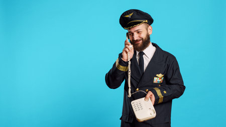 Commercial pilot talking on landline phone call in studio, answering office telephone with cord for...