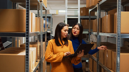 Female employees doing financial planning on laptop, checking products for supply chain management. Owner and female worker analyzing logistics data on pc, business development.の写真素材