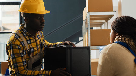 Warehouse employees working in cargo storehouse to prepare products for shipment, organizing carton packages on racks. Team of people using laptop for logistics and inventory in depot.の写真素材