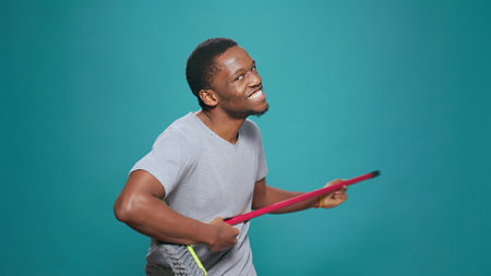 Portrait of foolish carefree singer playing guitar on broom, feeling positive about childish...