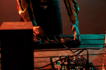 Musical artist mixing techno music on turntables, playing record mix sounds on audio dj instrument and stereo equipment. Enjoying nightclub party with stage production on studio background.の写真素材