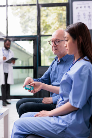 Asian physician nurse examining elderly patient with glucometer during consultation, measuring...