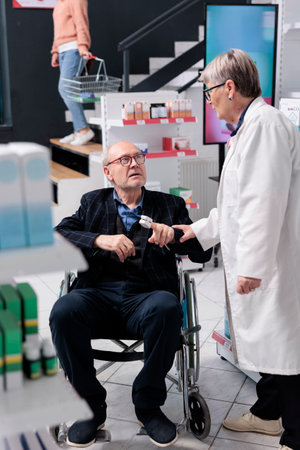 Wheelchair user talking with pharmacist about medical prescription while worker measuring...