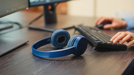 Professional video editor using wireless headphones on desk in creative agency studio, having...