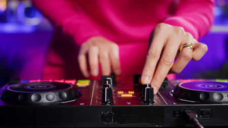 Dj artist creating unique techno sound using mixer console, performing at eletronic party in club at...