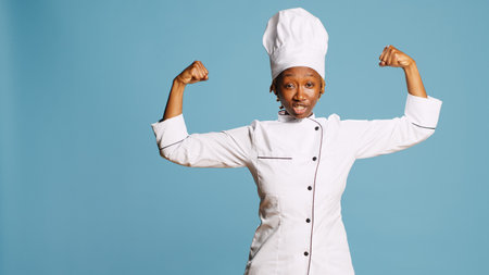 Powerful woman cook flexing arm muscles on camera, showing power and body strength in studio....