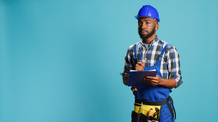 Young handyman making calculations on files, taking notes on papers before starting new construction...