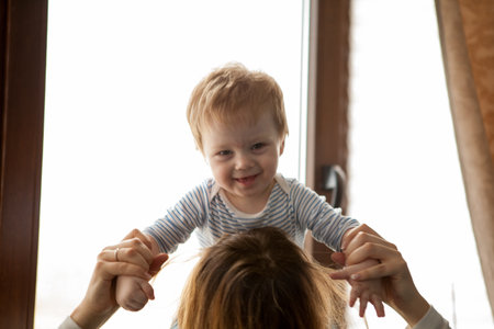 Mother with her beautiful kid looking at the window. Happy childhood and parentingの写真素材