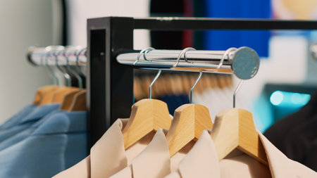 Empty retail store filled with racks and hangers, modern casual wear hanging in shopping mall shop. Fashionable boutique with clothes on sale, small business commercial activity concept.の写真素材