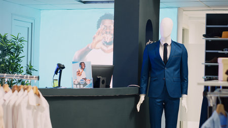Modern fashionable shop with clothes on hangers, stylish brand design and formal wear in department store. Empty clothing store with fitting rooms and merchandise, commercial activity.の写真素材