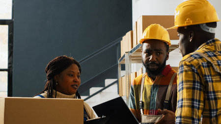 Male workers planning shipment with laptop in depot space, checking boxes with merchandise before doing distribution. Two men doing quality control in storage room, cargo stock.の写真素材