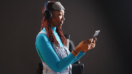 Young adult watching tv series on tablet in studio, using headset to watch online episodes of tv...