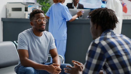 Group of people sitting in waiting room at hospital and talking about medical insurance support. Male patients waiting to attend examination, discussing about treatment or medicine.の写真素材