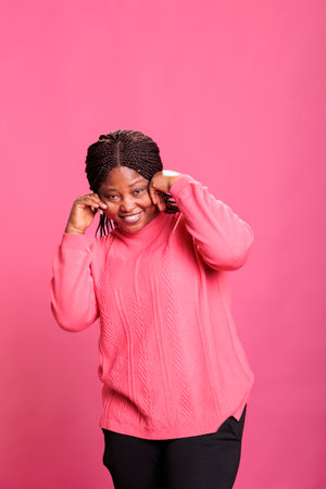 Young cheerful adult fooling around and being silly in studio, having fun in front of camera over background. Casual excited woman being positive and optimistic, enjoying laugh and smiling.の写真素材