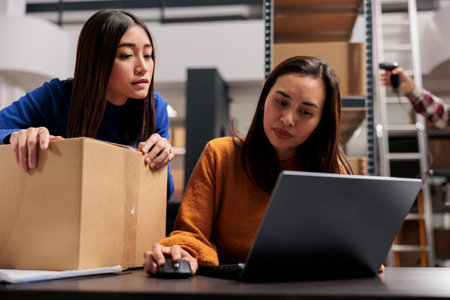 Storehouse asian workers doing parcel quality control and managing delivery. Ecommerce retail business warehouse young women coworkers tracking order shipment online on laptopの写真素材