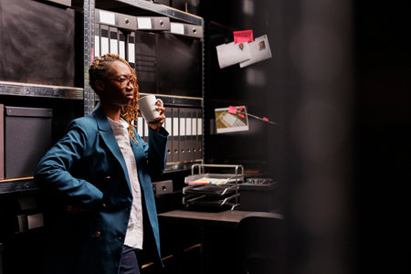 Concerned african american woman detective drinking coffee and thinking about crime case. Thoughtful...