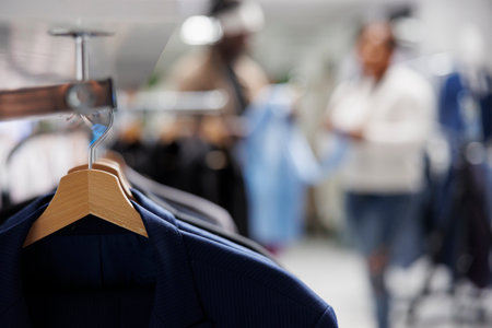 Trendy jackets on hangers in clothing store with blurred background. Casual modern blazers from new collection hanging on rack in department shopping mall close up selective focusの写真素材