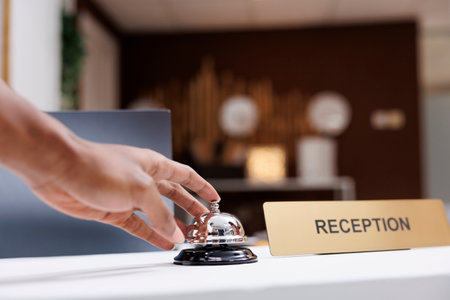 Guest ringing service bell at front desk, waiting to receive assistance from hotel staff at...
