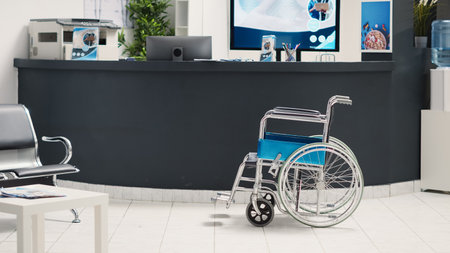 Empty disability friendly medical clinic with wheelchair in lobby, hospital reception front desk used for checkup visit appointments. Chronic impairment recovery in waiting room, seating at facility.の写真素材