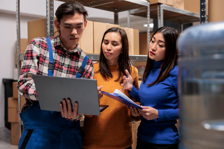 Warehouse employees managing parcel recieving and sending operation online on laptop. Storehouse...