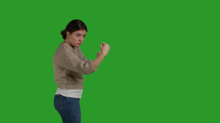 Side view of aggressive woman showing clenched fists in studioの写真素材