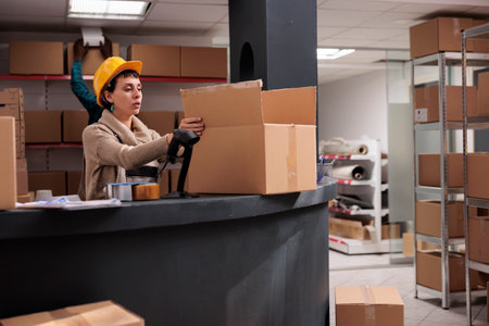 Warehouse operative putting products in box at counter deskの写真素材