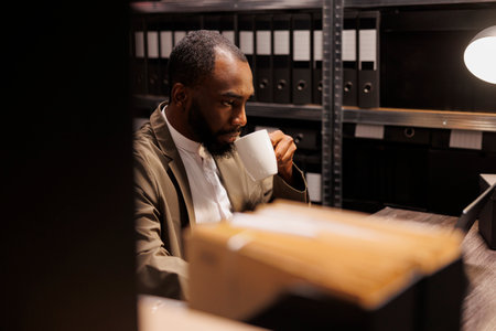 Policeman drinking coffee and analyzing clues using laptop