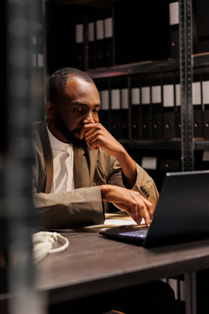 Tired cop thinking while solving case using laptop