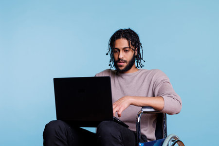 Arab man with physical impairment coding on laptopの写真素材