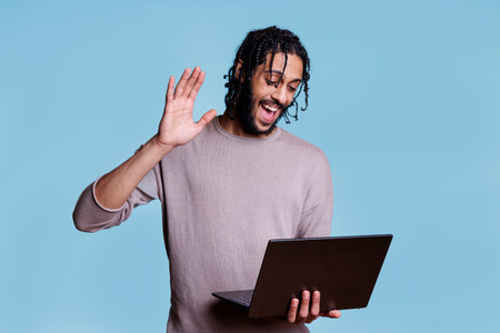 Cheerful man greeting customer in video call on laptopの写真素材