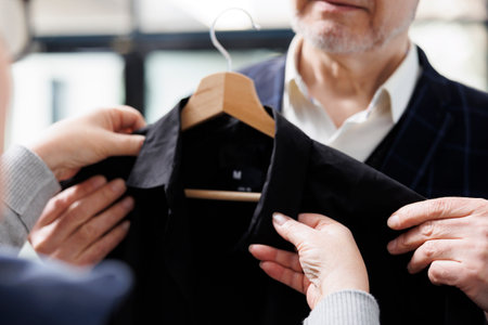 Elderly man trying stylish black shirt in showroomの写真素材