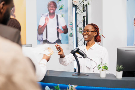 Smiling cashier taking clothes from customer at cash registerの写真素材