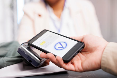 Close up of customer holding phone using nfc technology to pay for clothing, making digital payment...
