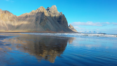 Massive mountain range meeting the ocean, beautiful icelandic landscapes with black sand beach. Arctic stokksnes peninsula with vestrahorn mountains and ocean coastline, sightseeing.の写真素材