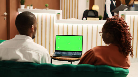 Happy company coworkers away on business trip talking with management on laptop chroma key green screen mock up. Employees travelling for work sitting in hotel lounge waiting to be checked inの写真素材