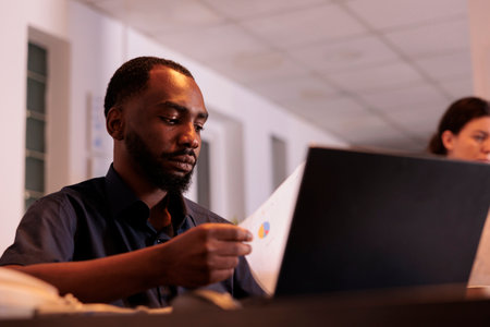 Employee analyzing report statistics data, working on laptop in office, planning company financial...