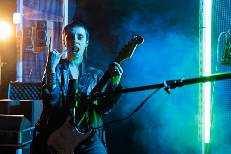 Guitarist woman standing in front on microphone while playing at electricguitar working at rock...
