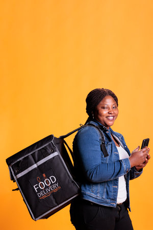 Restaurant delivery employee holding smartphone looking at customer adreess on fast food app before...