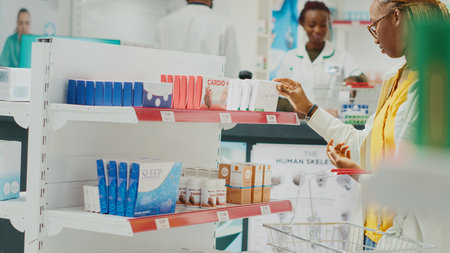 African american client looking at drugs on shelves, buying medicaments and healthcare products from drugstore. Young customer taking pills or vitamins from racks. Handheld shot.の写真素材