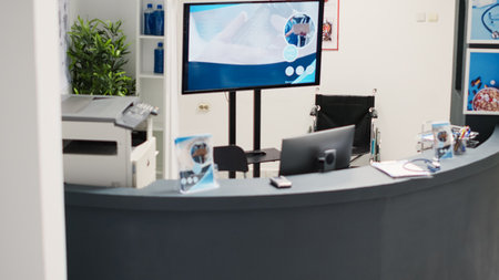 Healthcare facility reception desk in waiting room with registration forms and checkup appointment reports. Empty counter in clinical lobby used for recovery service, cure disease. Handheld shot.の写真素材