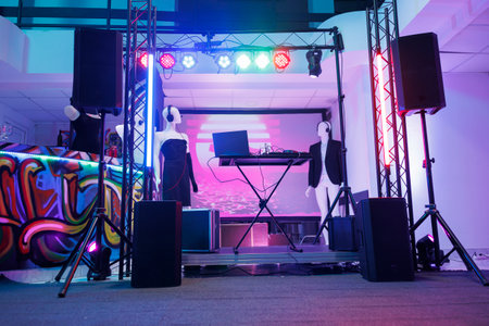 Dj controller on stage for discotheque in empty nightclub with no people. Electronic musician console equipment, loudspeakers and spotlights for live music concert in dark club.の写真素材