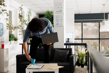 Arab young businessperson holding laptop in start up business office. Entrepreneur putting coffee mug on table to work at company marketing strategy plan on computer after breakの写真素材