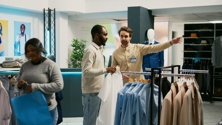 African american shopper taking clothes in fitting room to dress up, trying on merchandise to buy new fashion collection. Young man client visiting retail shop market boutique.の写真素材