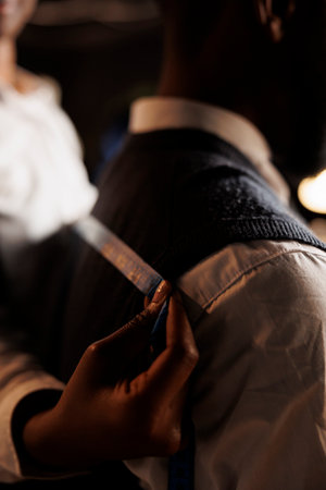 Extreme close up of meticulous skilled tailor taking sartorial stylish garment measurements on...